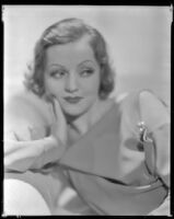 Nancy Carroll, actress, in a salon in front of a fireplace, circa 1933-1935