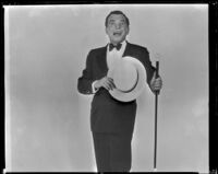 Man holding a hat and cane and possibly singing, circa 1926-1939