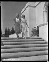 Woman and Louise Stanley, actress, walk hand in hand down a set of stairs, circa 1938