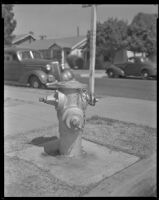 Fire hydrant with cars and houses in background, circa 1926-1939