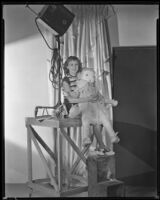 Barbara Read, actress, sitting on a wooden platform holding a large doll, circa 1934-1936