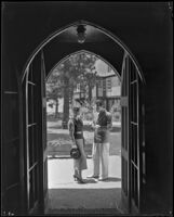 Johnny Mack Brown, actor, and a woman seen through an arched doorway, Lake Arrowhead, circa 1929-1934