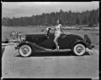 Woman wearing a bathing suit and standing on the running board of a car, Lake Arrowhead, circa 1929-1934