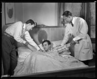 Fred Keating, actor, at home in bed in his Hollywod Hills home, assisted by 2 men, Los Angeles, 1934