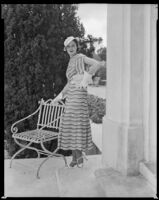 Woman holding a purse and leaning on a chair in front of what may be the Hotel Del Monte, circa 1932-1939