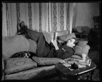 Fred Keating, actor, on a sofa with his dog in his Hollywood Hills house "Casa Escrow," Los Angeles, circa 1934