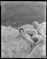 Woman standing on the rocks above the ocean, circa 1932-1939
