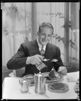 Gene Raymond, actor, pouring syrup on pancakes, circa 1933