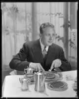 Gene Raymond, actor, cutting pancakes, circa 1933