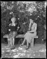 Louise Stanley, actress, eating an ice cream while another woman looks at a notebook, Claremont, circa 1938
