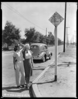 Louise Stanley, actress, shielding her eyes while she and another woman look up at a sign, Claremont, circa 1938