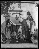 Louise Stanley, actress, pointing at a fountain while another woman leans on it, Claremont, circa 1938