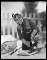 Woman strapping on snowshoes, circa 1929-1934