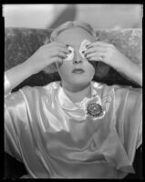 Virginia Pine, actress, holding cotton swabs over her eyes, circa 1934-1935