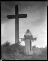 Billie Seward, actress, standing in front of a cross dressed as a nun, circa 1934-1935