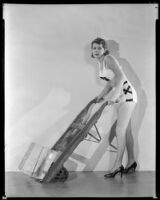 Billie Seward, actress, pushing a dolly carrying a block of ice, circa 1934-1935
