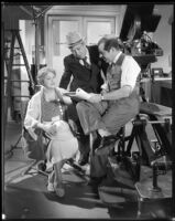 Albert Rogell, director, showing a script to Clara Kimball Young, actress, and a man, circa 1935-1938