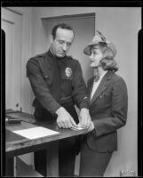 Marian Marsh, actress, having her fingerprints taken by a police officer, Los Angeles, circa 1935-1939