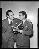 Theodore Pratt, author, holding a copy of his novel, Mr. Winkle Goes to War, while another man drapes his arm over Mr. Pratt's shoulders, circa 1944