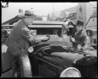 Charlie Murray and George Sidney, actors, cleaning the windshield of a car, circa 1930-1934