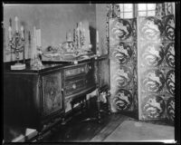Sideboard with silver and candles on top, along with a screen covering a window, 1936