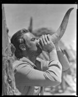 William Holden, actor, drinking from an animal horn on the set of Arizona, circa 1940
