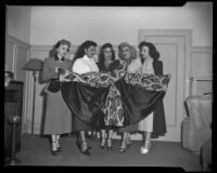 Charlita, actress, and four women admiring an embroidered cape, circa 1951