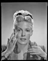 Janis Carter, actress, applying a beauty product to her face, 1946