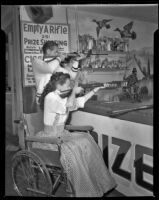 Susan Peters and husband Richard Quine, actors, playing carnival rifle game, circa 1947-1948