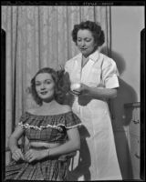 Gloria Henry, actress, and a beautician applying a hair treatment, circa 1947-1951
