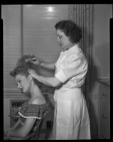 Gloria Henry, actress, having her hair brushed by a beautician, circa 1947-1951