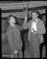 Man standing under a glider with Glenn Ford, who is in costume as John J. Montgomery from Gallant Journey, 1946