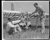 Man sitting in a glider as a man sits in the grass and another man on crutches stands by (possibly during filming of Gallant Journey), copy print, 1946