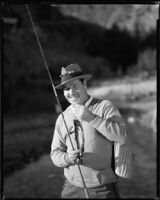 Jack Holt, actor, holding a fishing pole with a stream and hill in the background, perhaps considered for a Movie Mirror magazine feature, 1927-1939