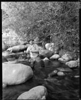 Jack Holt, actor, standing in a stream fishing, perhaps for a Silver Screen magazine feature, 1927-1939