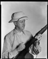 Clyde E. Elliott, producer and director, holding a rifle, circa 1934