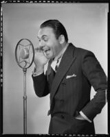 Edward Buzzell, director and actor, speaking into a microphone, circa 1931-1935