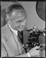 David Burton, director, looking at a film camera, circa 1933-1934