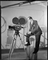 Albert Rogell, director, standing with a film camera, circa 1929-1938