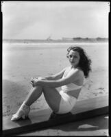 Geneva Mitchell, actress, sitting on a beach, circa 1931-1936
