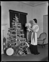 Geneva Mitchell, actress, holding a stuffed pig and standing next to a Christmas tree, 1934