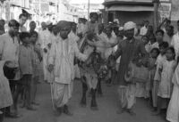 Bison and musician playing a drum in a crowded street, Miraj (India), 1963