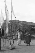 Banjara (or Lambadi) man and woman in village beside prayer (?) flags, Hyderabad, vicinity (India), 1963