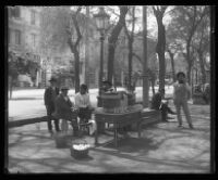 Men relax and sell drinks on a city sidewalk.